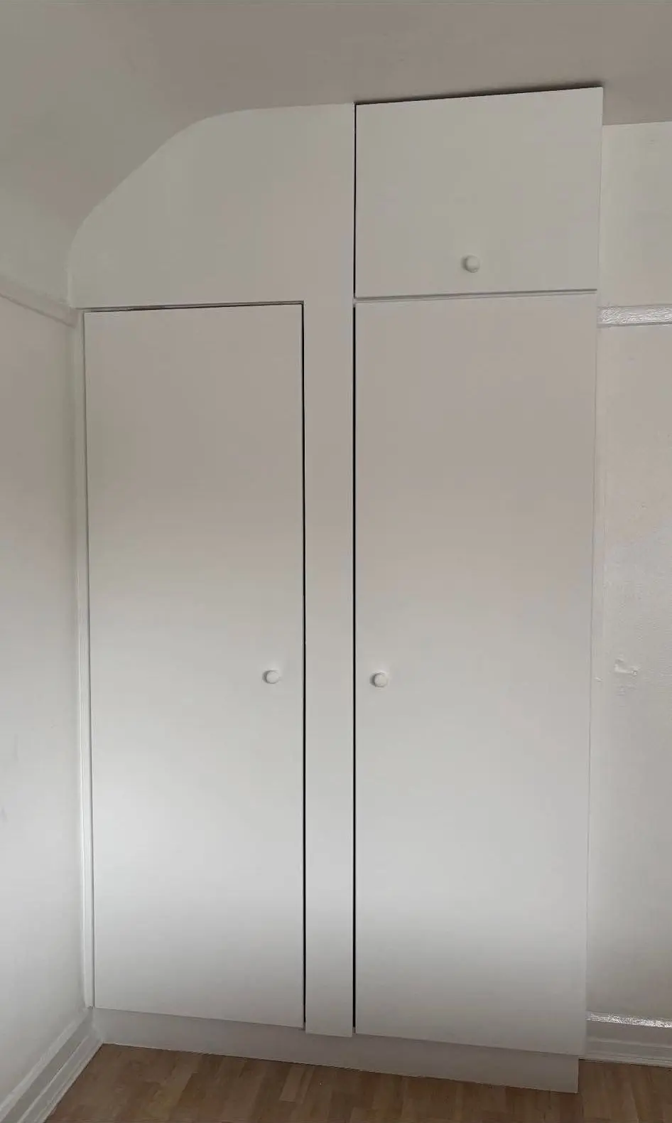 White fitted wardrobe filling an alcove up to the ceiling coving