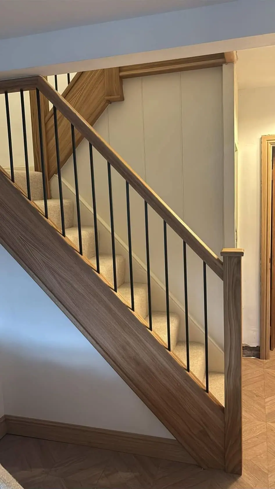 Refurbished staircase with an oak handrail, oak newel posts and black steel spindles