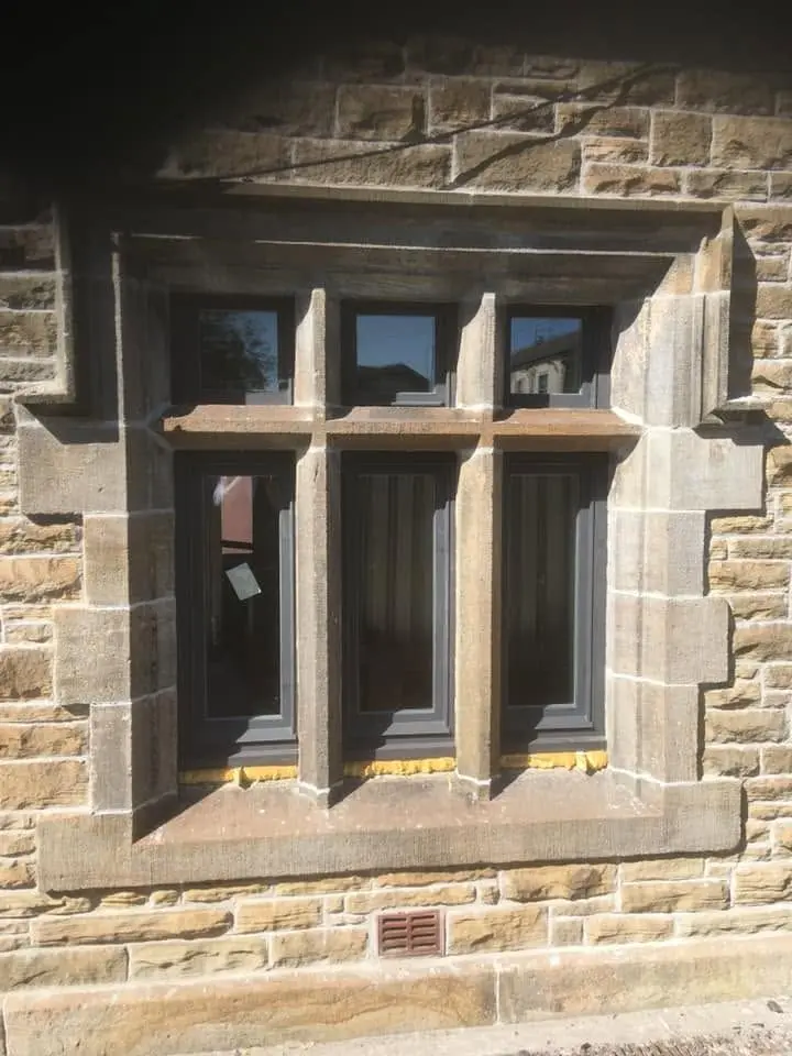 Painted timber window with leaded-style glazing bars set in a sandstone mullion surround